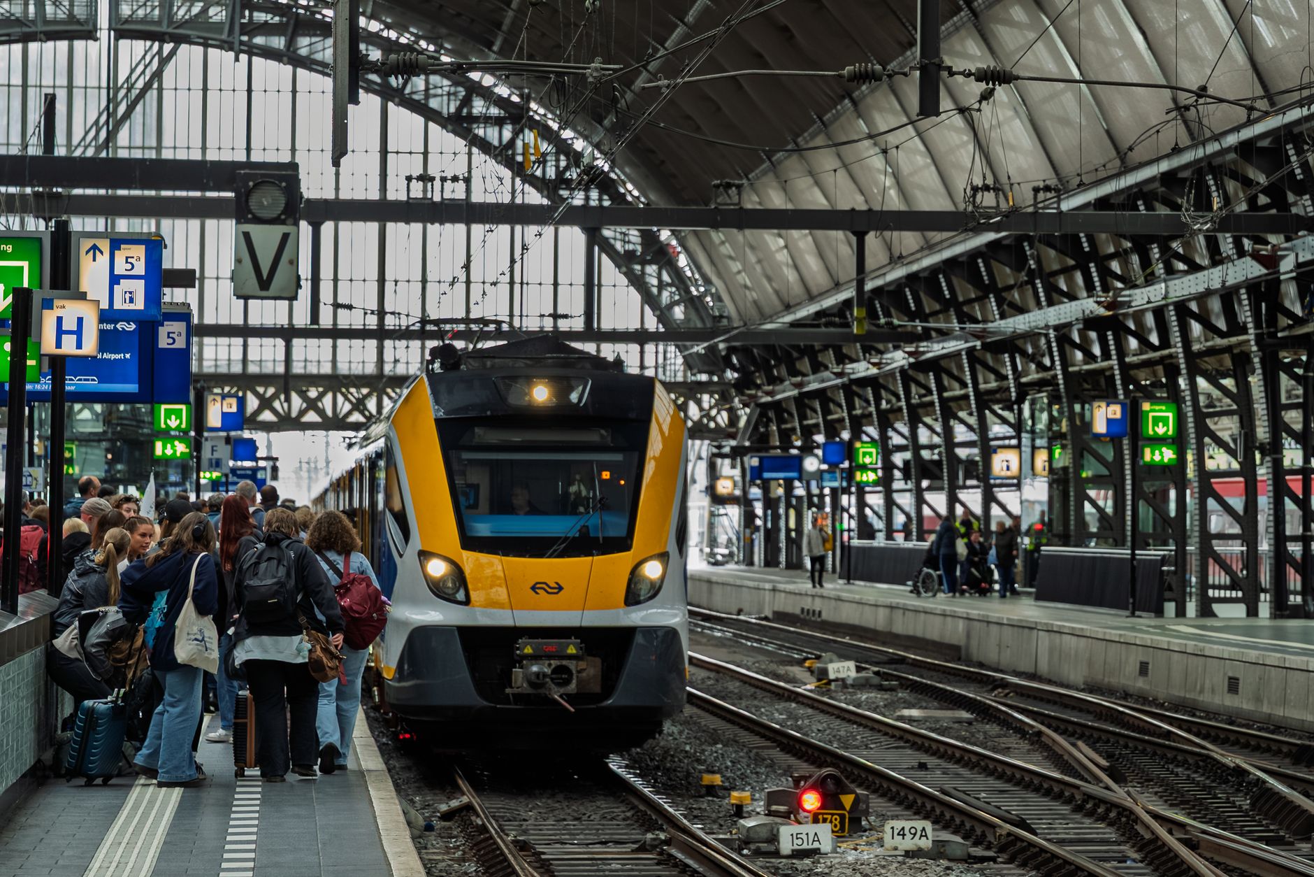 Tłoczny peron na Amsterdam Centraal i wjeżdżający pociąg